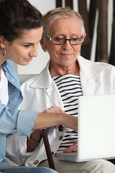 Äldre kvinna använder laptop med vårdare — Stockfoto