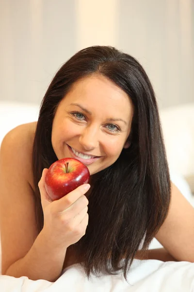 Γυμνή γυναίκα τρώει ένα μήλο στο κρεβάτι — Φωτογραφία Αρχείου