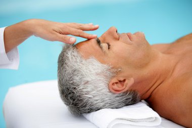 Mature man having facial massage clipart