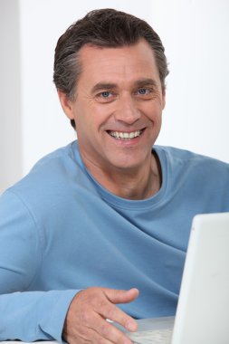 Smiling man using a laptop computer clipart