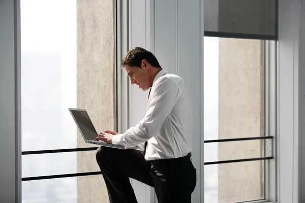 Üzletember dolgozik laptop ablak közelében — Stock Fotó