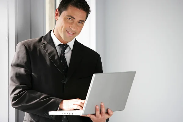 Человек стоял в офисе, держа ноутбук — стоковое фото