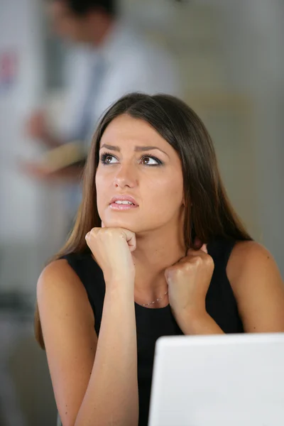Confused brunette sat with laptop — Stock Photo, Image
