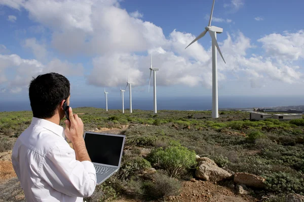 Jovem empresário ao telefone ao lado de turbinas eólicas — Fotografia de Stock