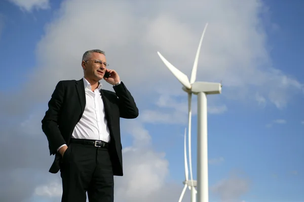 Mężczyzna na telefonie komórkowym obok turbiny wiatrowej — Zdjęcie stockowe