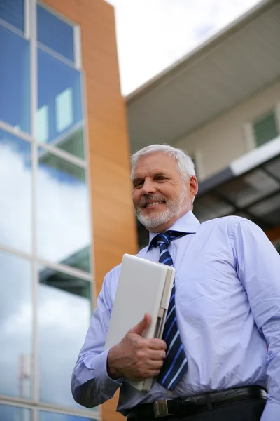 Senior zakenman houdt laptop buiten — Stockfoto
