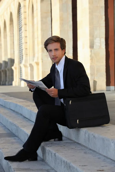 Elegant unga arbetande människan sitter på trappan — Stockfoto