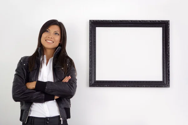 Young woman stood by empty picture frame — Stock Photo, Image