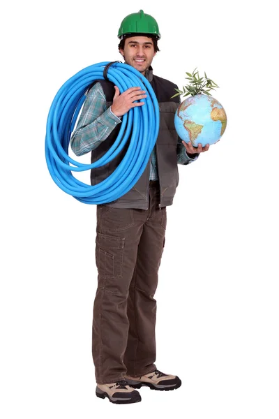 Artigiano in possesso di un tubo flessibile e un globo con una pianta verde su di esso — Foto Stock