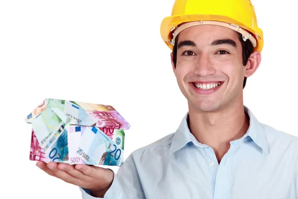 An architect holding a miniature of a house made of banknotes. — Stock Photo, Image