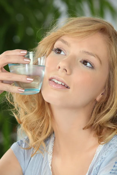 Молода блондинка зі склянкою води проти щоки — стокове фото