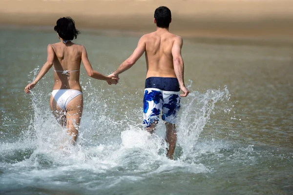 Couple running through the water — Stock Photo, Image