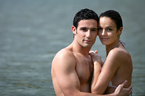 Par embracing medan du badar i havet — Stockfoto