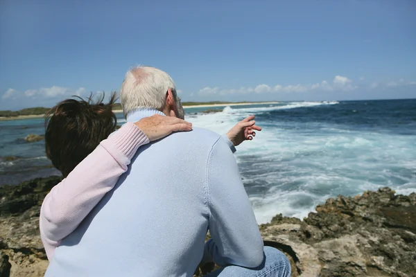 Seniorenpaar zeigt aufs Meer — Stockfoto