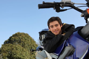 Adolescent boy posing with his motorcycle clipart