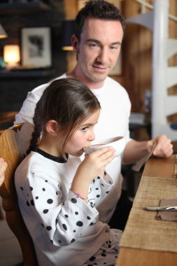 Girl drinking hot chocolate with her father clipart