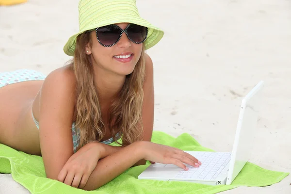 Mädchen liegt mit Laptop am Strand — Stockfoto