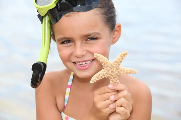 Menina na praia segurando estrela peixe — Fotografia de Stock