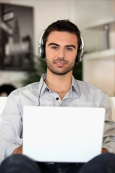 Young music lover with earphones and laptop — Stock Photo, Image