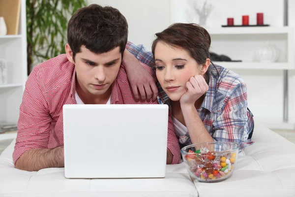 Jeune couple utilisant un ordinateur portable à la maison — Photo