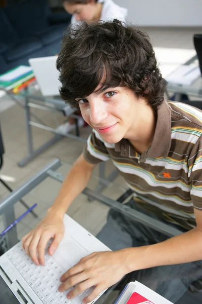 Teenager s notebookem v jeho schooldesk — Stock fotografie