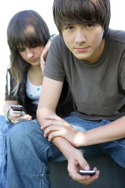 Adolescente casal mensagens de texto em seus celulares — Fotografia de Stock