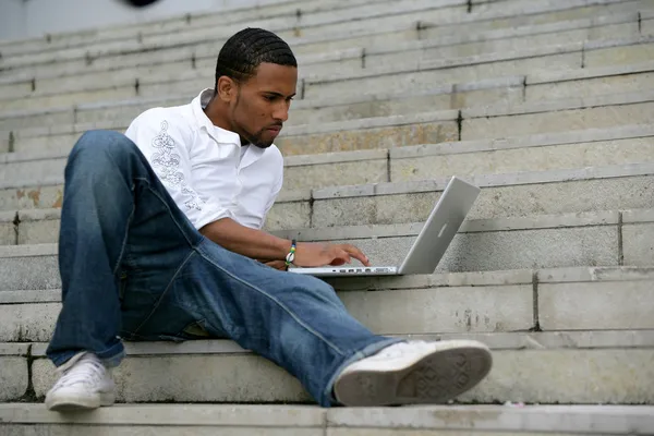 Homme noir travaillant sur ordinateur portable dans les escaliers — Photo