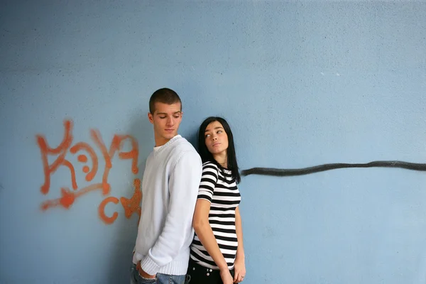 Casal jovem ficou perto de parede coberta de grafite — Fotografia de Stock