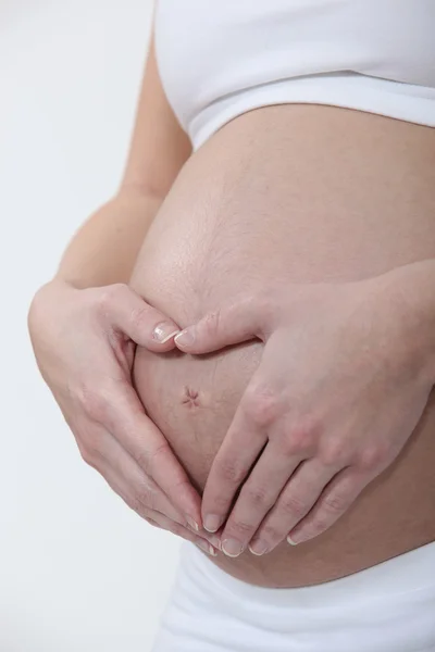 女性は彼女の妊娠中の腹を抱き締める — ストック写真