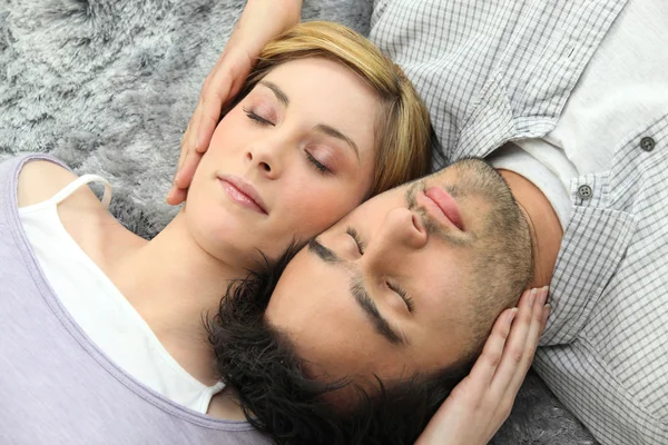 Pareja durmiendo en alfombra gris — Foto de Stock