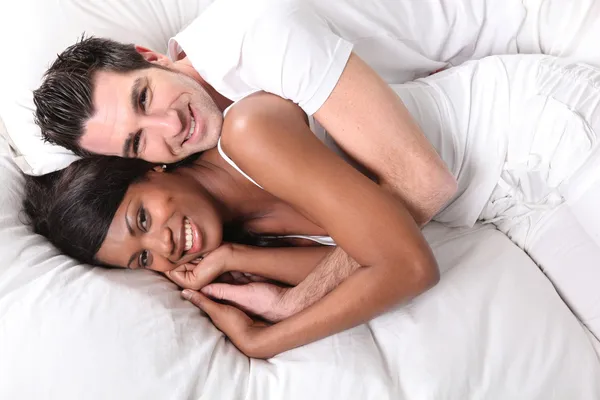 Interracial par på sängen — Stockfoto