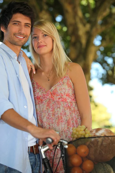 Summery couple with a basket of fruit — Stock Photo, Image