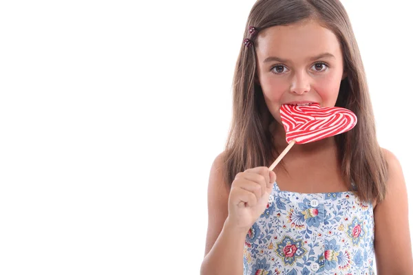 Rapariga comendo um pirulito em forma de coração — Fotografia de Stock