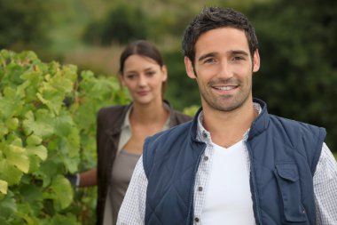 Young farmer stood with wife in vineyard clipart