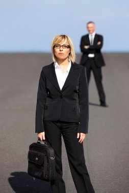 Blonde businesswoman standing far apart from her colleague clipart