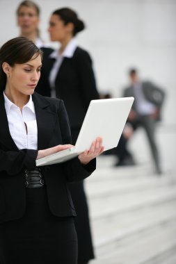 Businesswoman with a laptop in the city clipart