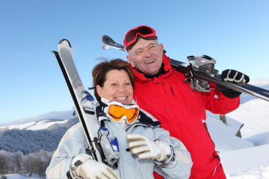 Retired couple having fun on a skiing trip clipart