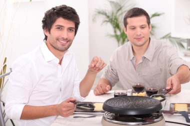 Men eating raclette clipart