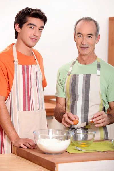 A young man and an old man making a cake — Stock Photo, Image
