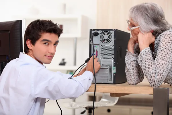 Молодой человек пытается починить компьютер — стоковое фото