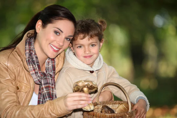Ung kvinna och liten flicka plocka svamp på landsbygden — Stockfoto