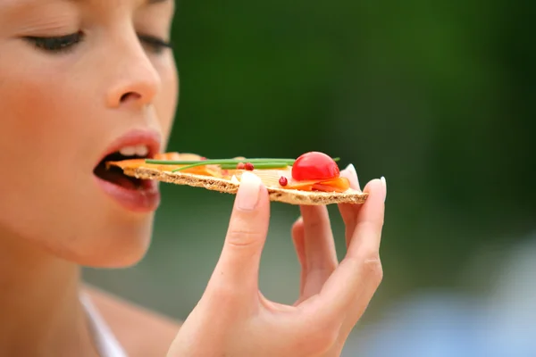 Жінка їсть здорову закуску крекерів — стокове фото