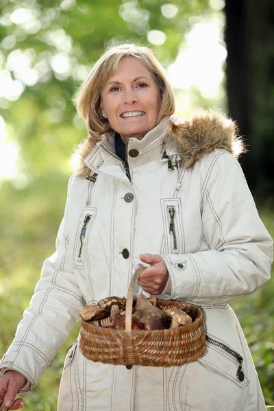 一个成熟的女人抱着一个蘑菇篮 — 图库照片