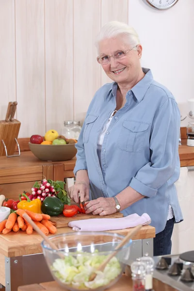 Пожилая женщина режет овощи — стоковое фото