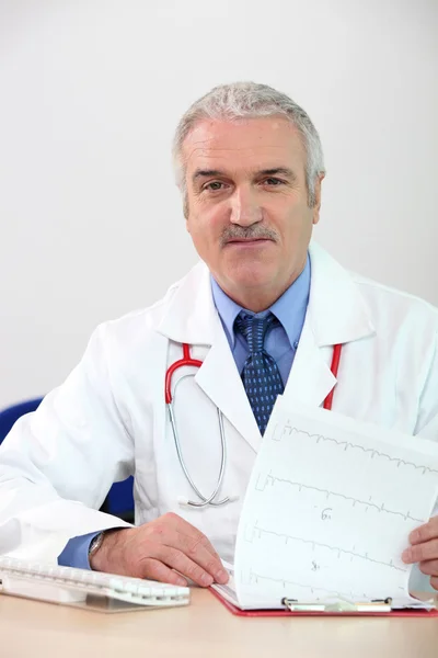 Mature doctor with clipboard and computer — Stockfoto