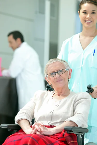 Seniorin im Rollstuhl mit junger Krankenschwester — Stockfoto