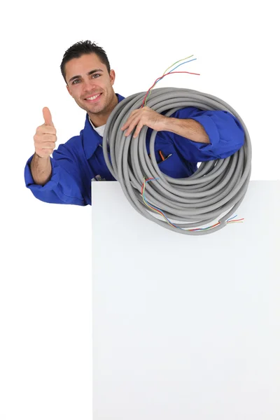 Электрик с длинным кабелем, показывающим большие пальцы вверх — стоковое фото