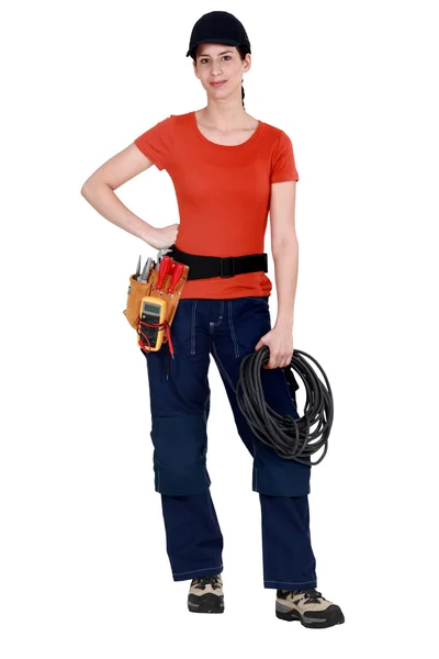 Handywoman holding cabling and wearing a tool belt — Stock Photo, Image