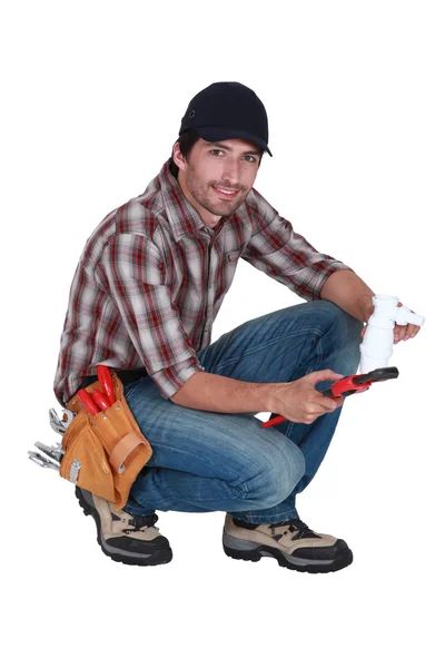 Plumber holding a plastic pipe and a spanner — Stock Photo, Image