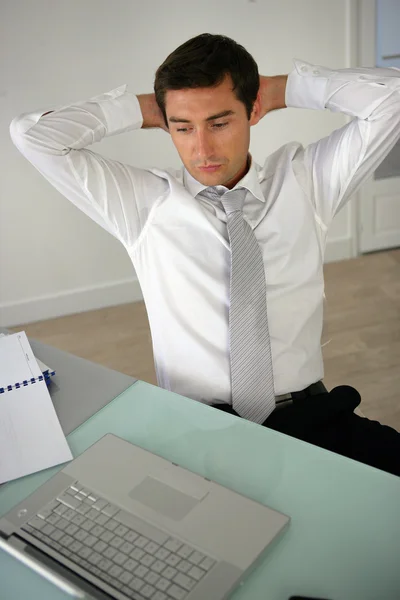 Hombre con las manos detrás de la cabeza en su escritorio — Foto de Stock